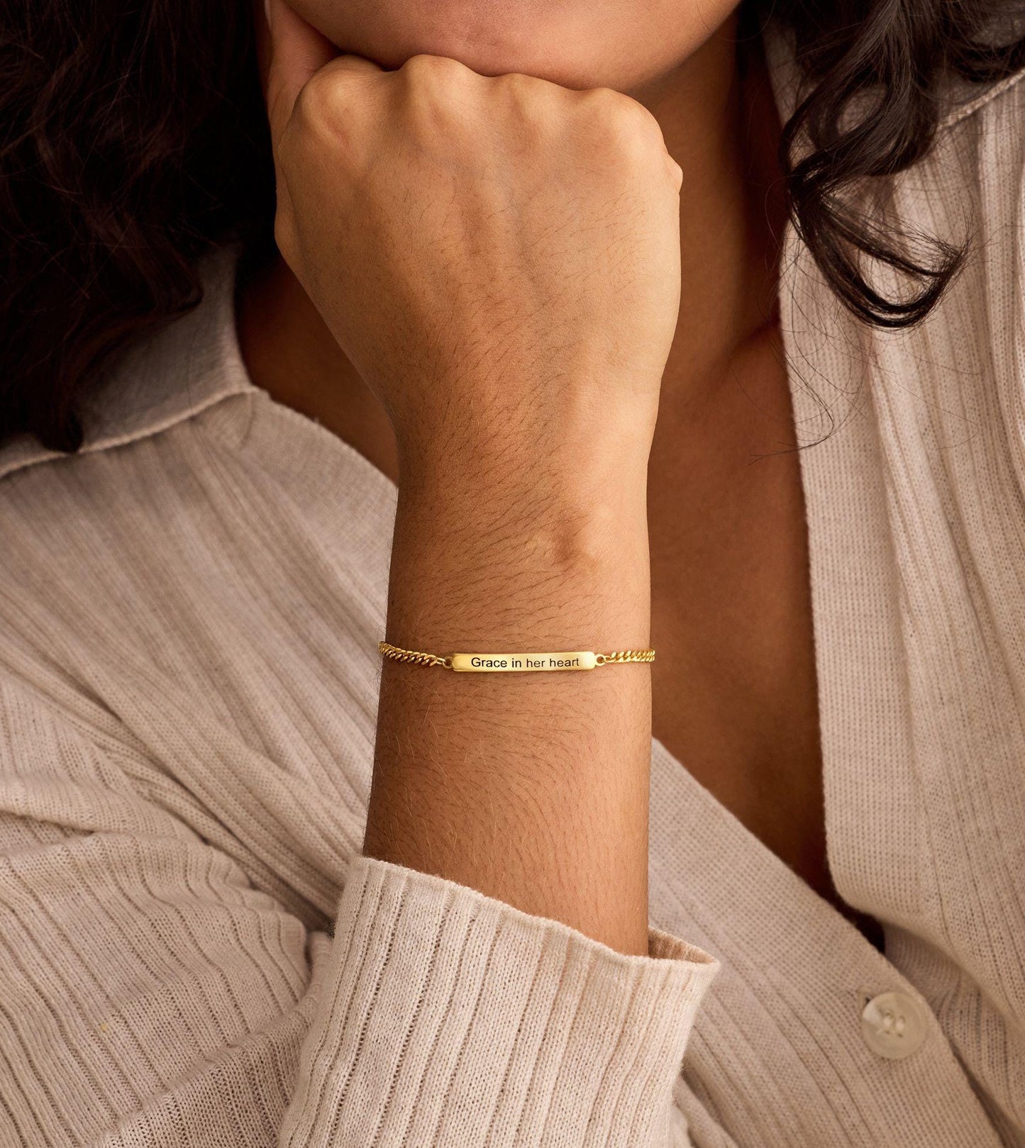 Gold bracelet on a wrist with a neutral background